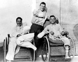 Posed Photo of Disabled Veterans, two in wheelchairs and one in the center missing an arm